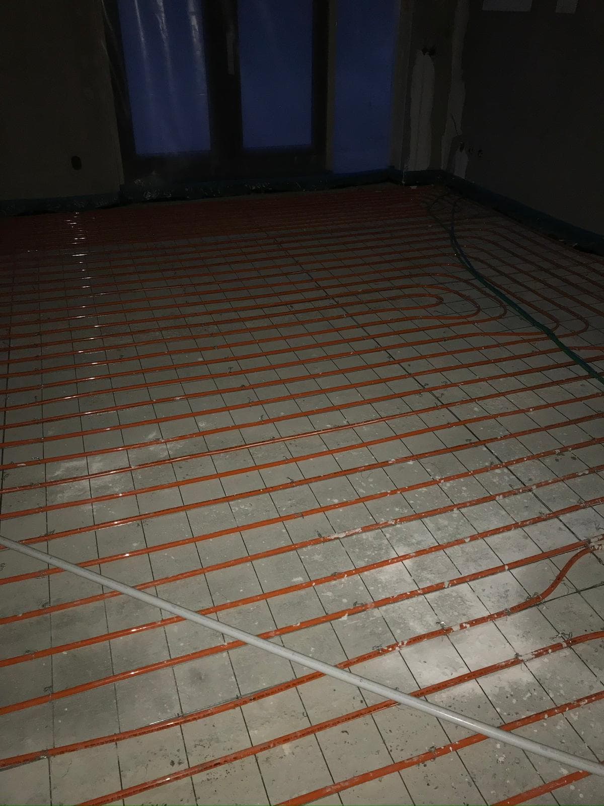Vloerverwarming groot vertrek met oranje leidingen netjes in slingerpatroon gelegd
