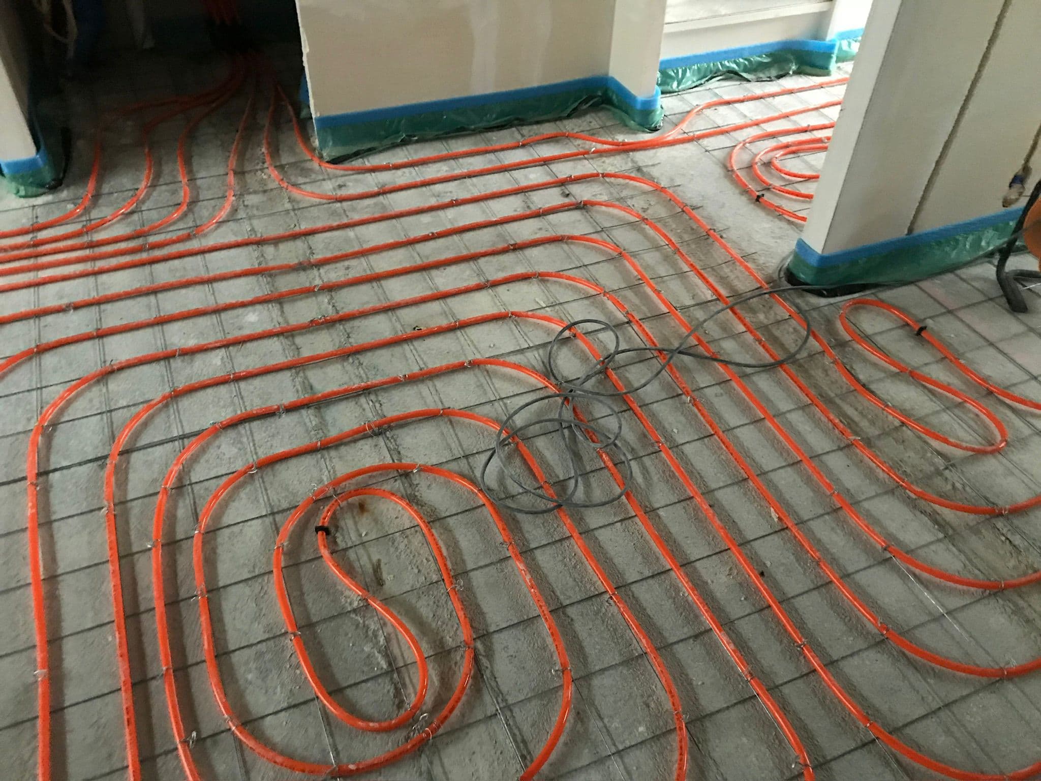 Vloerverwarming aanleg in groot woonvertrek, oranje leidingen op isolatieplaten