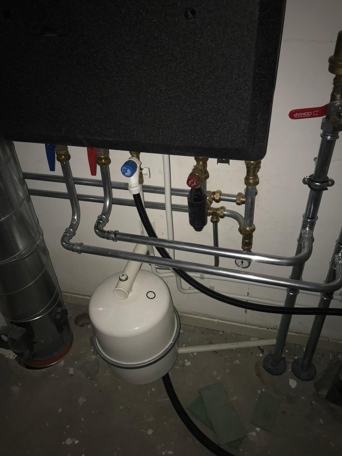 Aansluitingen onder warmtepompinstallatie met wit expansievat